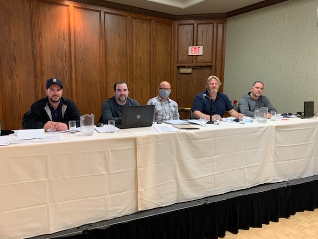 Five people posing for a photo at a long table