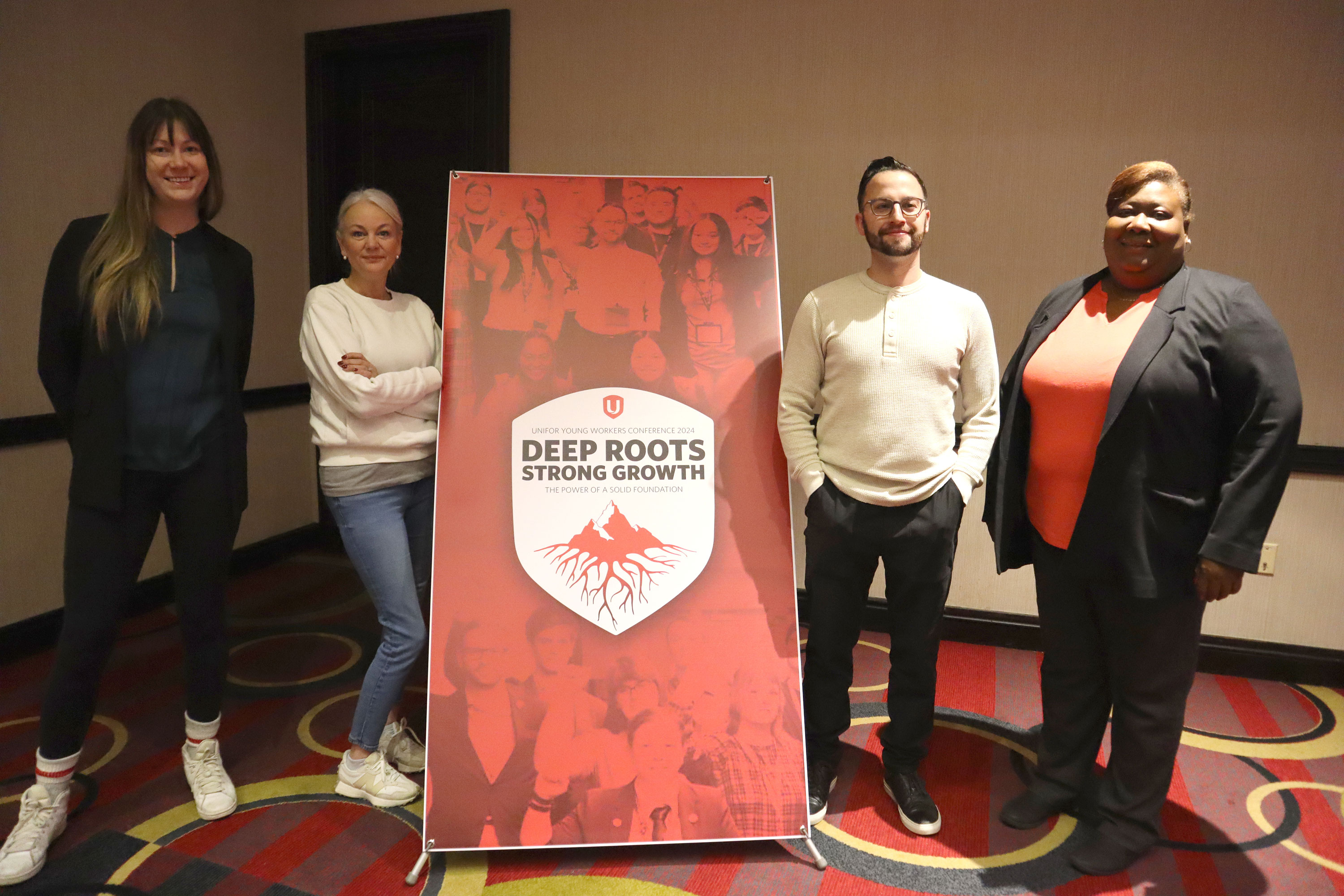 Four people standing beside a pop up banner.