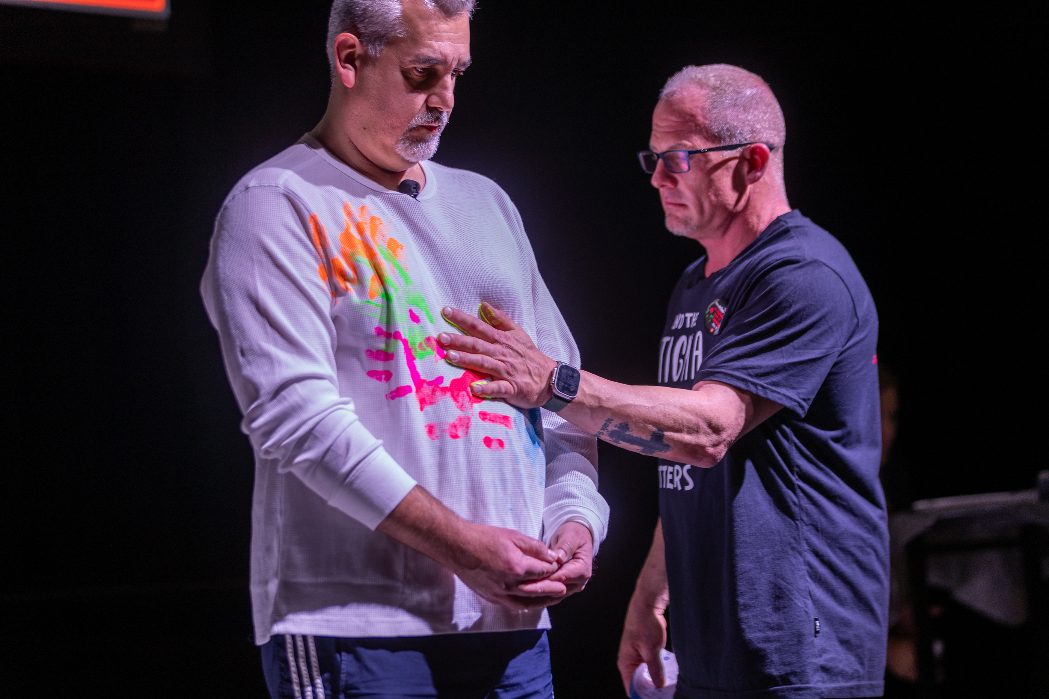 Two men standing facing one has his hand on the other.