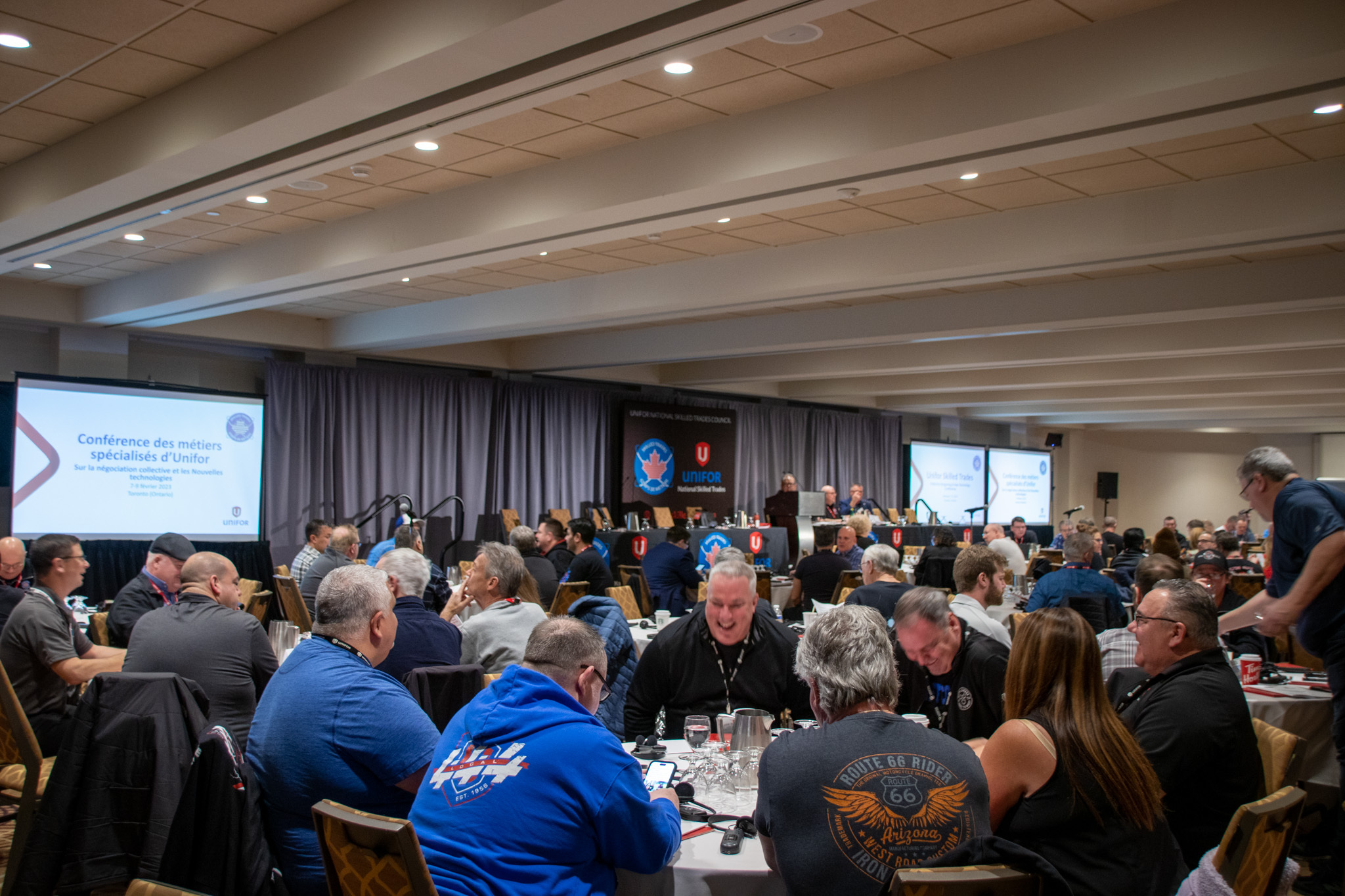 Délégués assis à la conférence d'Unifor 2023 sur les négociations collectives et les nouvelles technologies dans le secteur des métiers spécialisés.