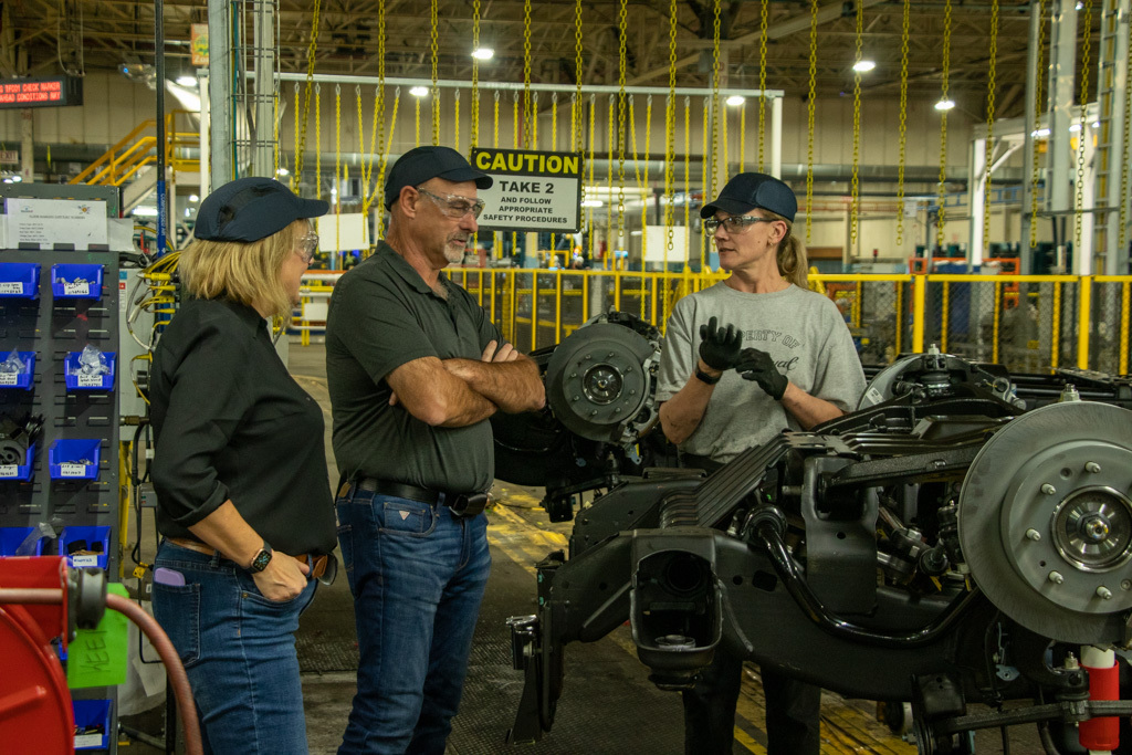 Unifor National President Lana Payne, National Secretary-Treasurer Len Poirier, and a Unifor Local 222 member stand on the assembly line at the General Motors Oshawa plant.