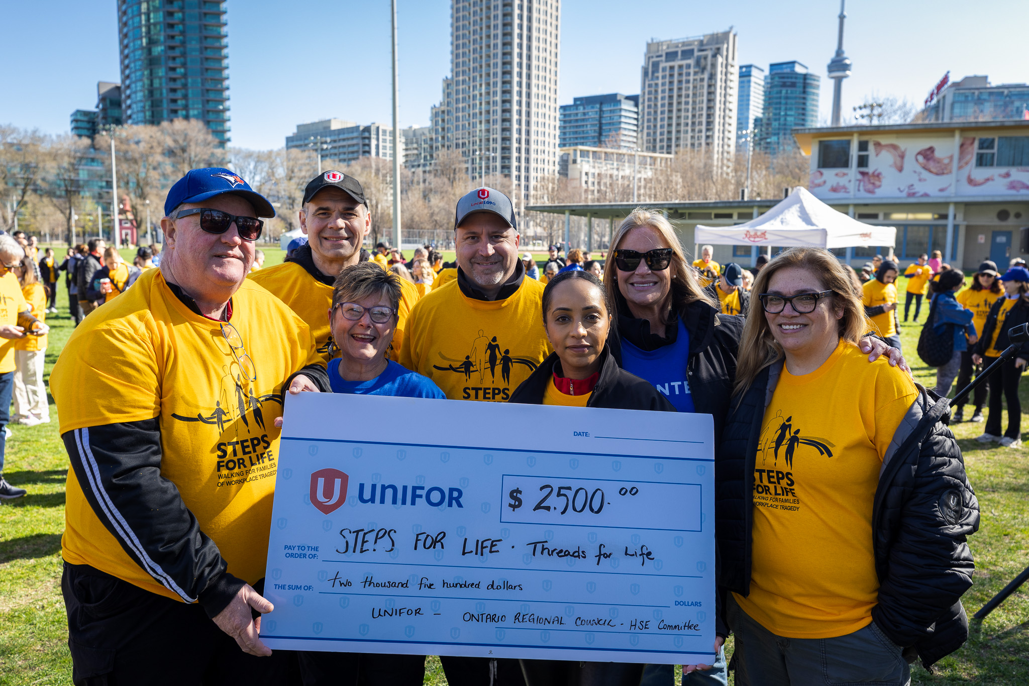 Six people gathered holding a oversized cheque
