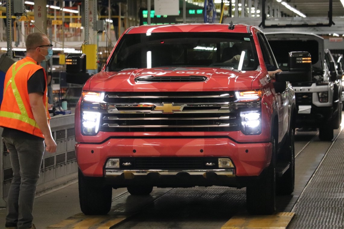 A Unifor member at GM Oshawa watches red truck roll off assembly line.
