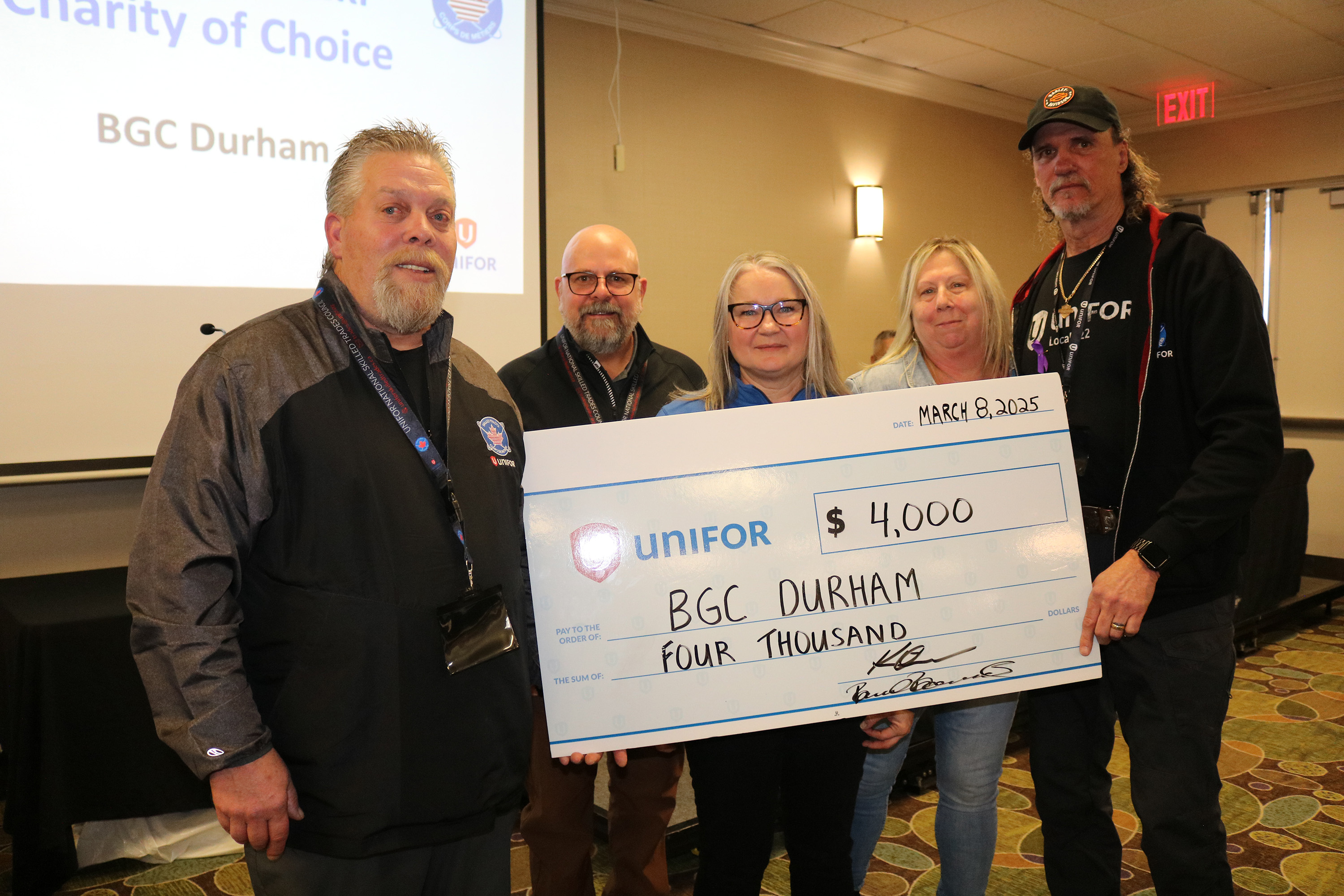 Five people holding up a oversized cheque