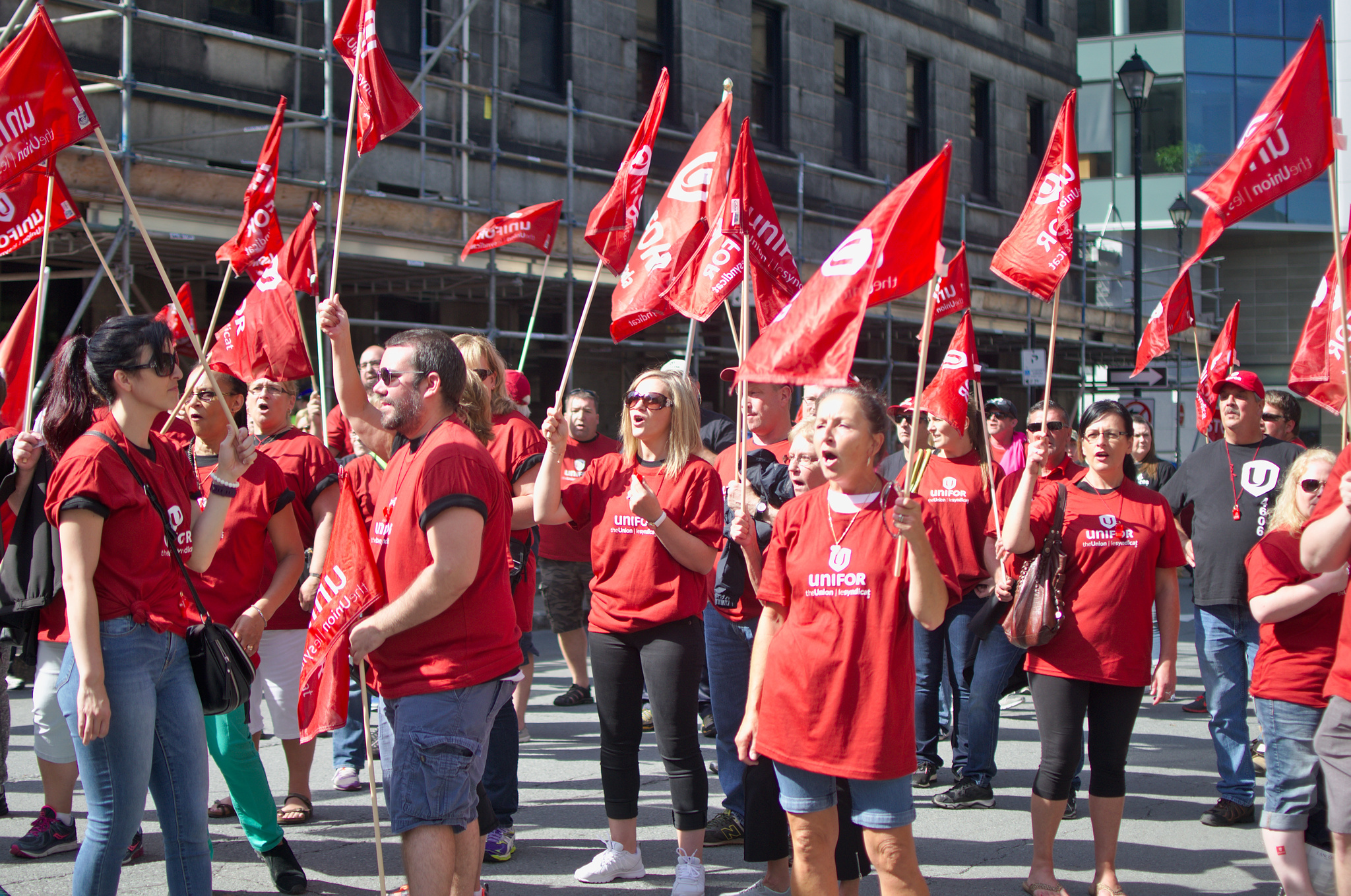 A group of Unifor members wearing, red and waving flags