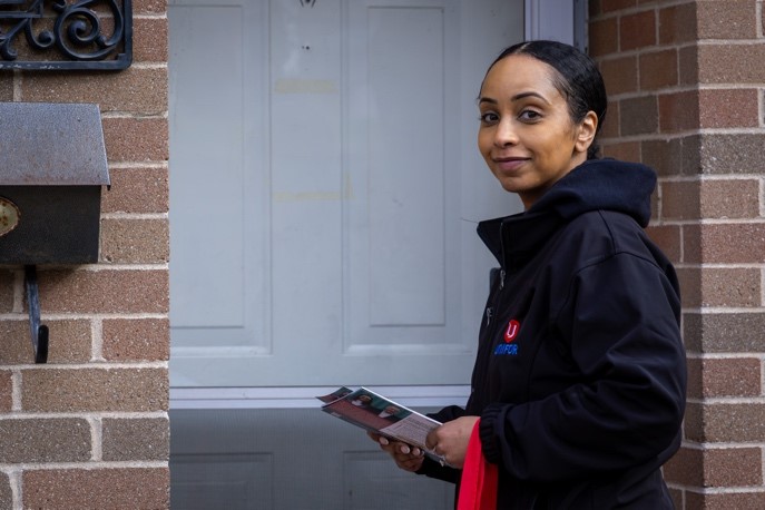 A women cavassing at a door with flyers