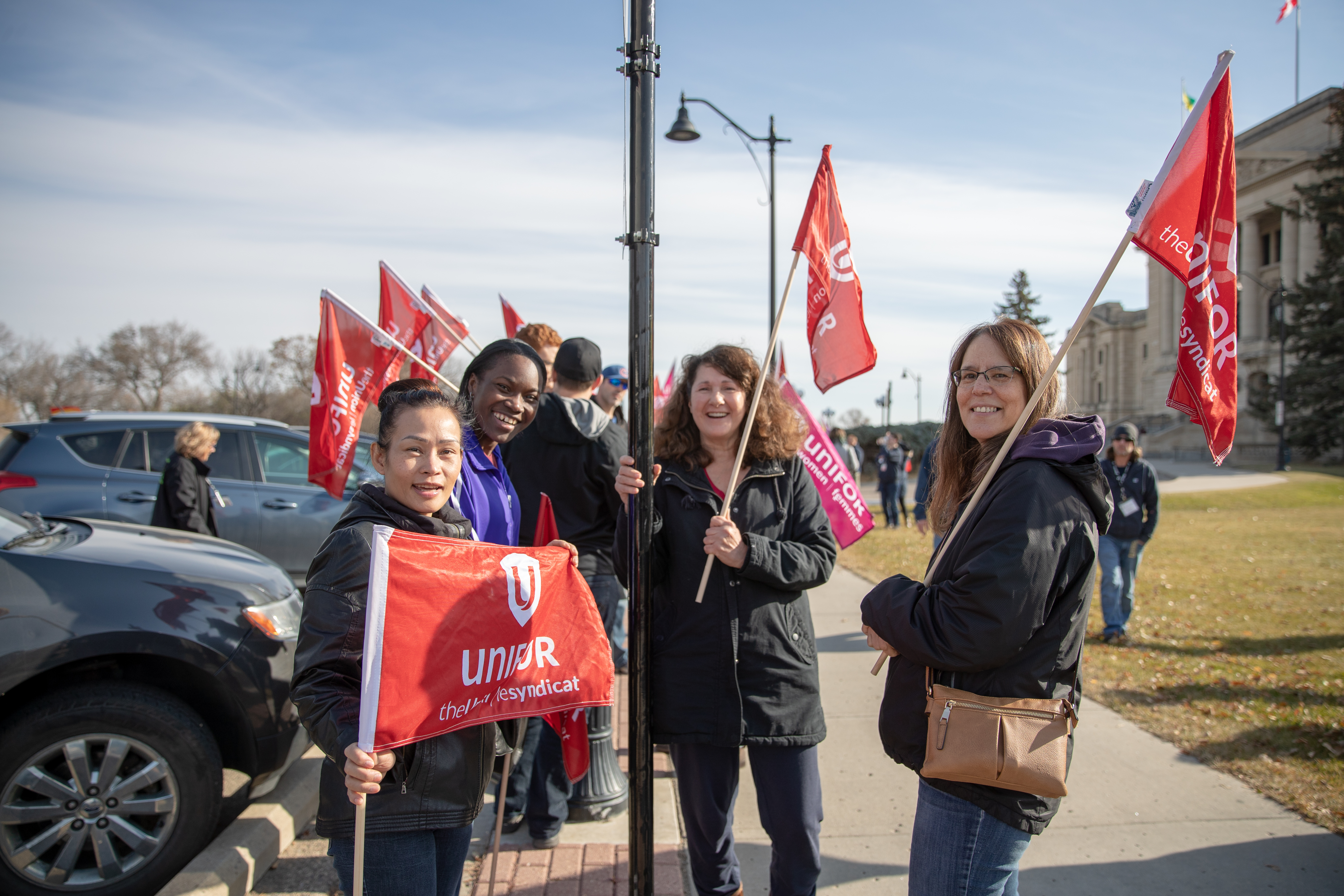 Women carrying Unifor flags gather in a group.
