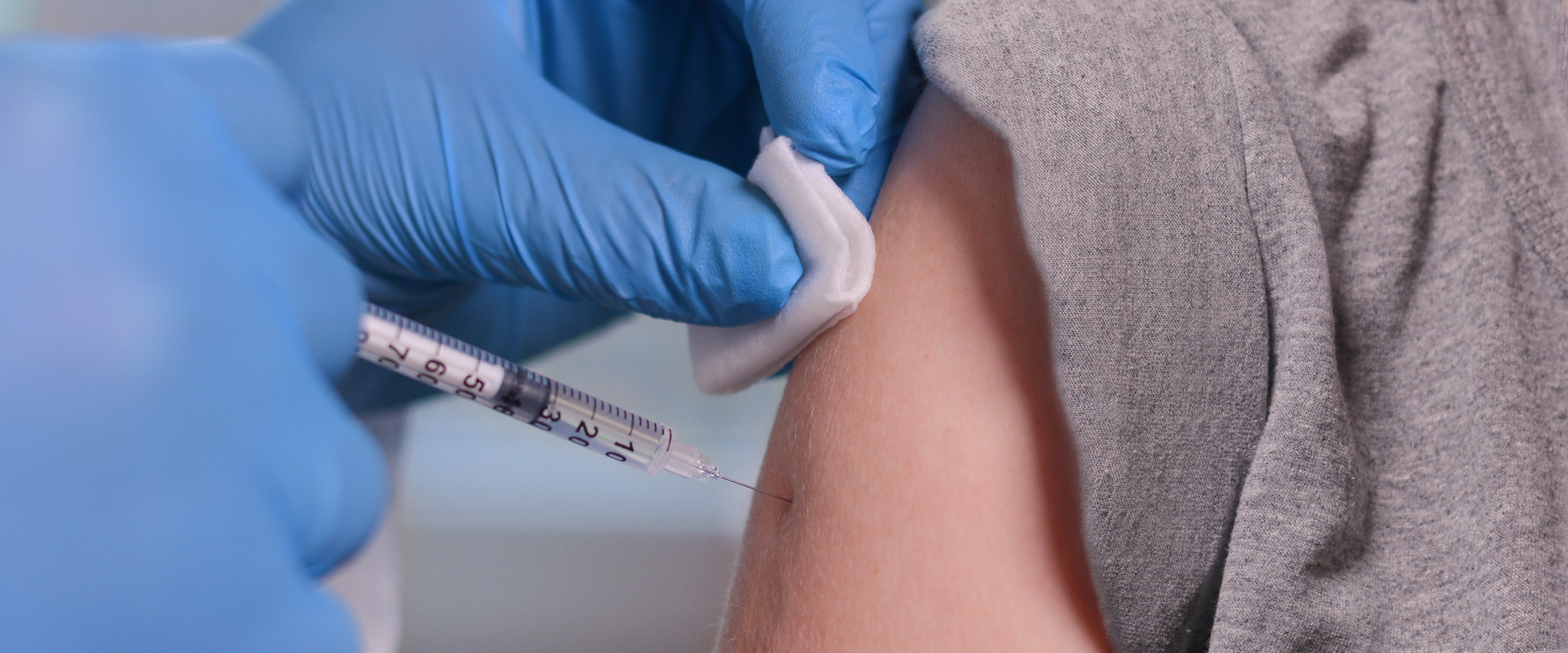 image close up of a needle jabbing an arm, someone getting a vaccine