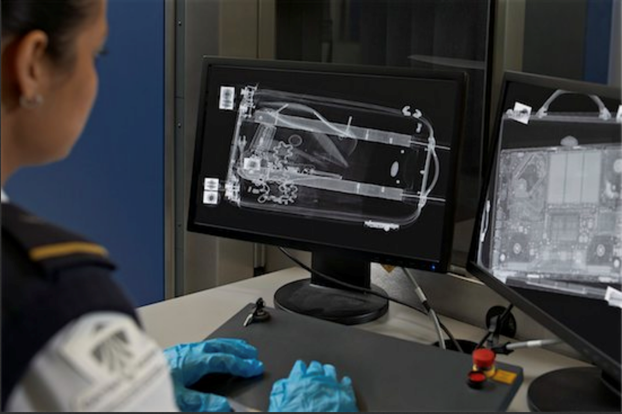 Une agente de contrôle de l'aéroport examine des images radiologiques de bagages.