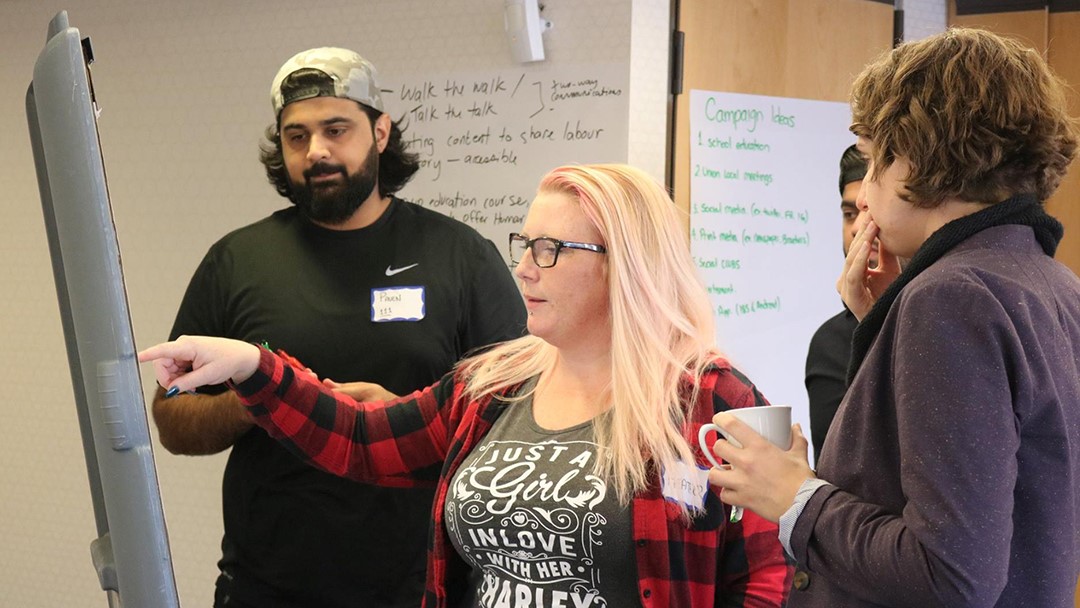 Four BC Council delegates hold a discussion around an easel.