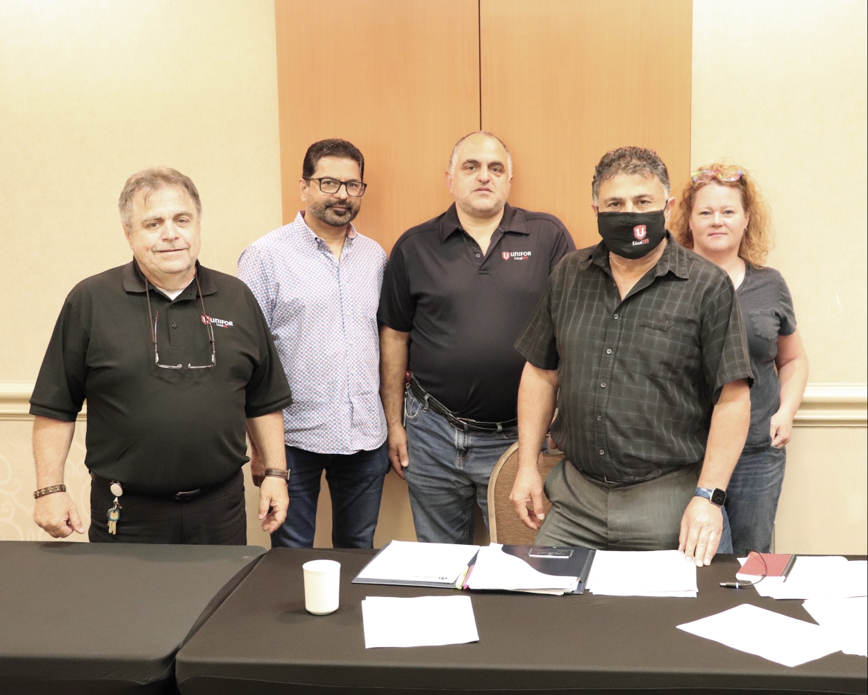 5 members of the bargaining commitee stand in front of a boardroom