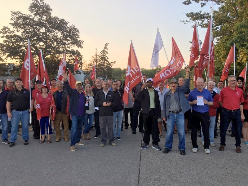 Unifor members hold flags at a rally.