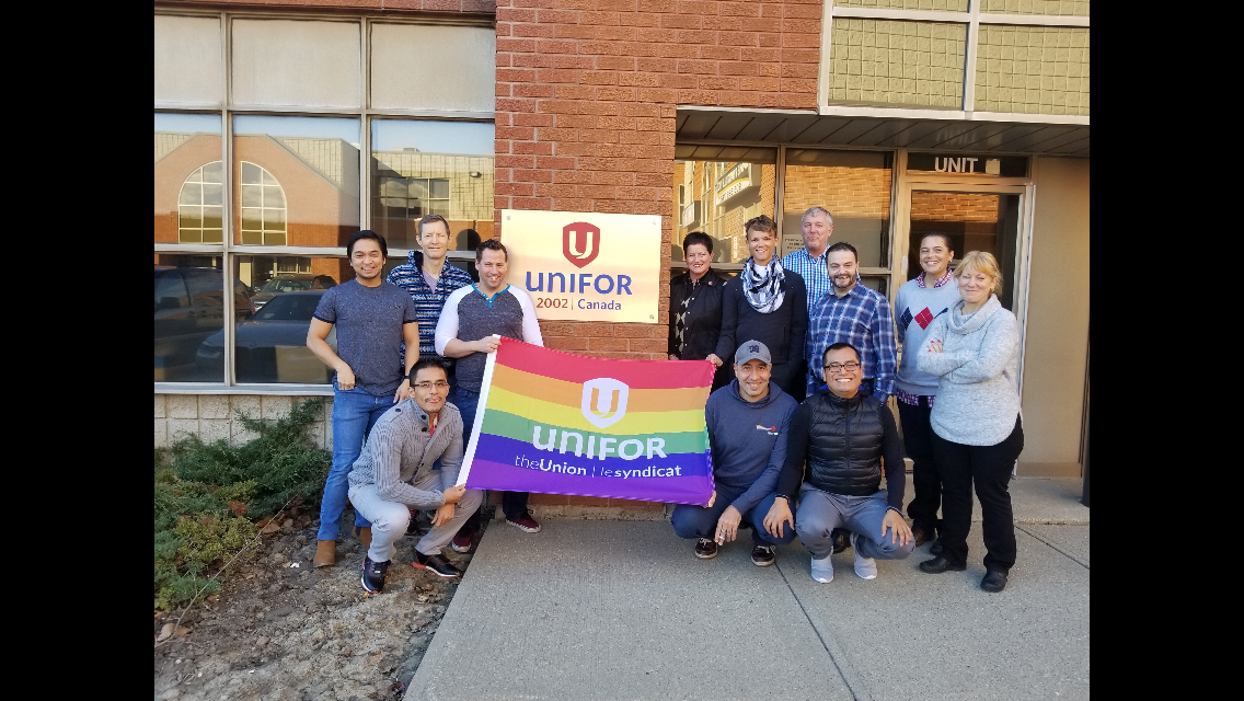 Members of Unifor Local 2002 hold a pride flag outside their Local office.