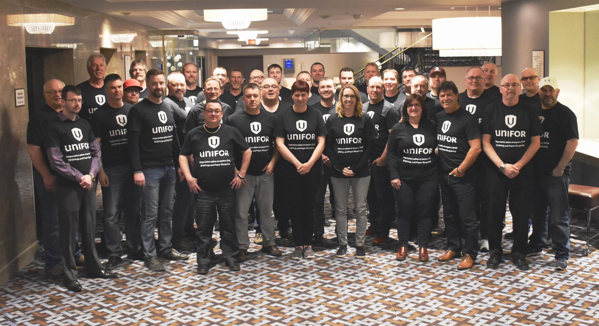 Renaud Gagné and a group of Unifor members wokring forestry stand in a hotel lobby wearing matching black t-shirts.