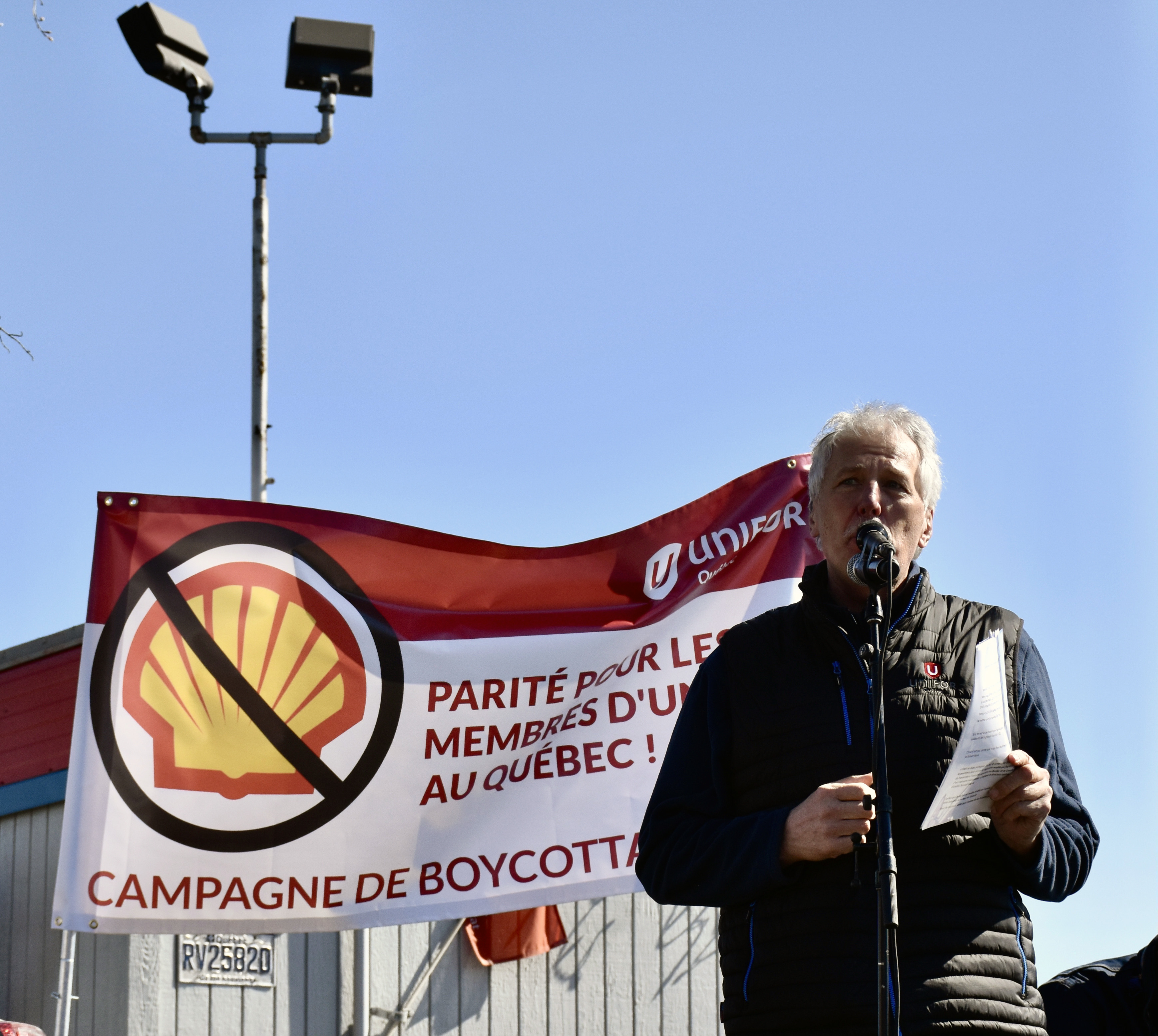 Unifor Quebec Director Renaud Gagné standing in front of a Unifor flag boycott of Shell products in Montreal