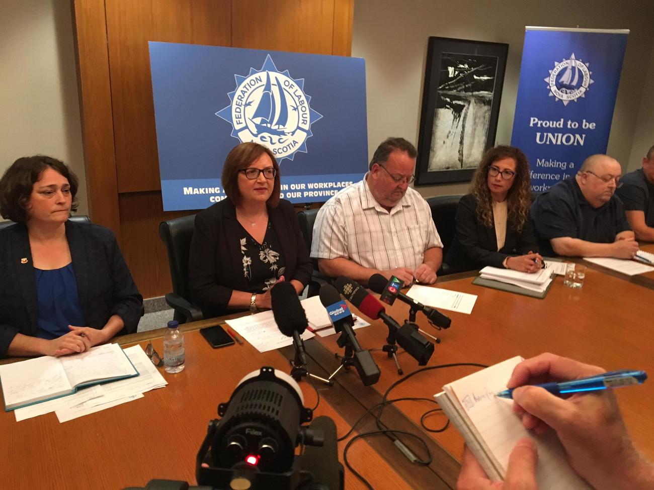Lana Payne and Nova Scotia Federation of Labour President Danny Cavanagh sit behind a row of microphones at a press conference.