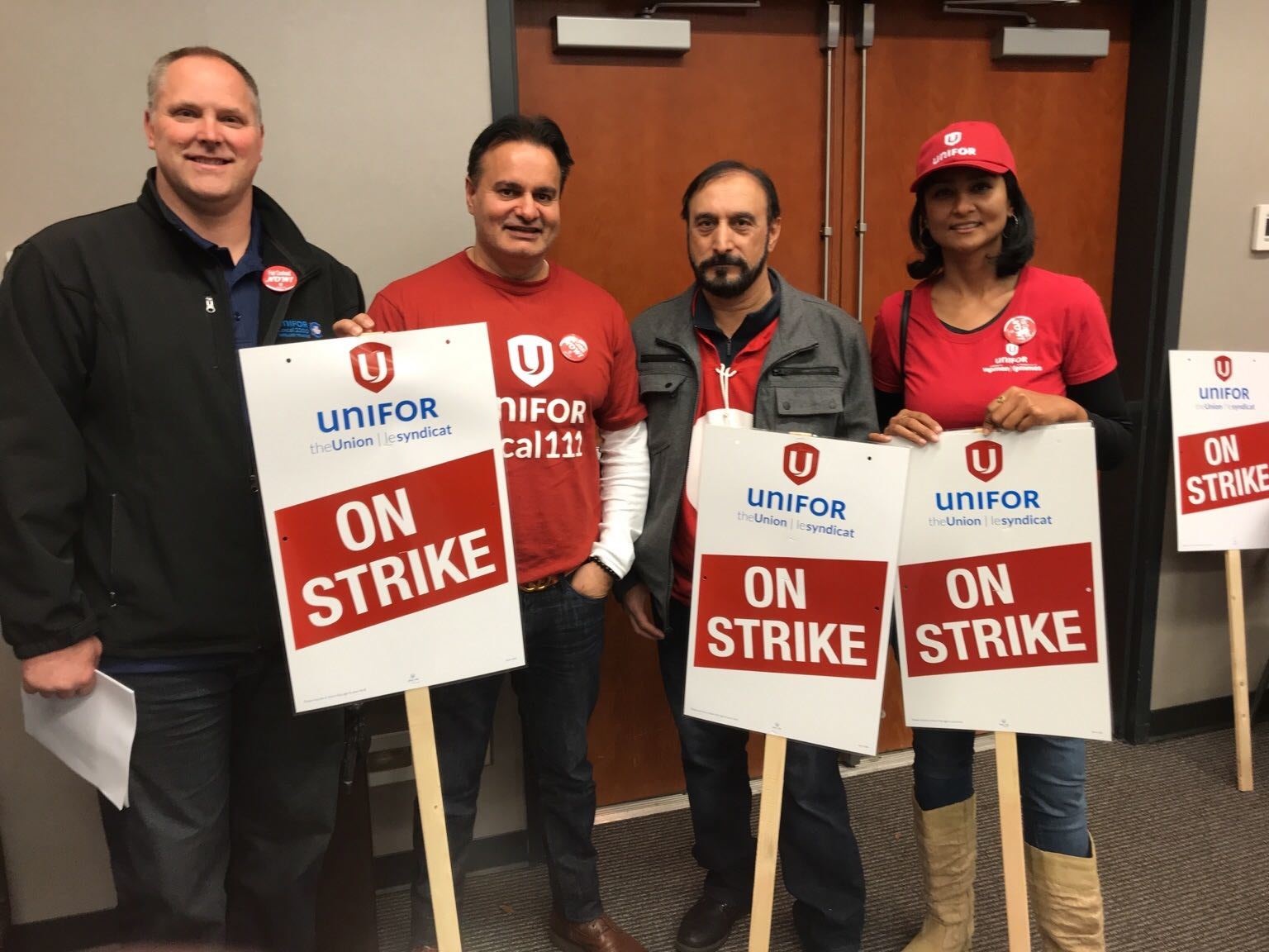 Unifor members hold strike signs.