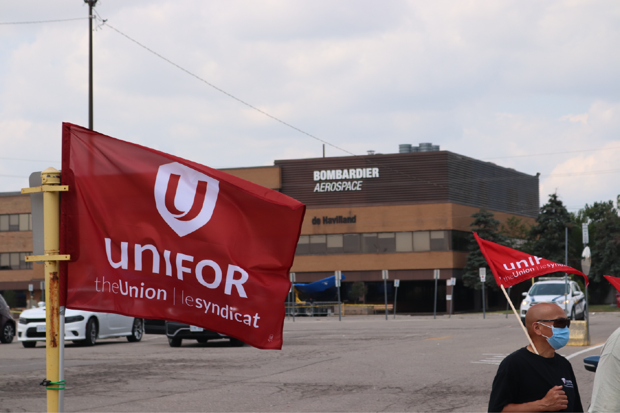 Unifor flag blows in wing in front of building witg Bombardier sign
