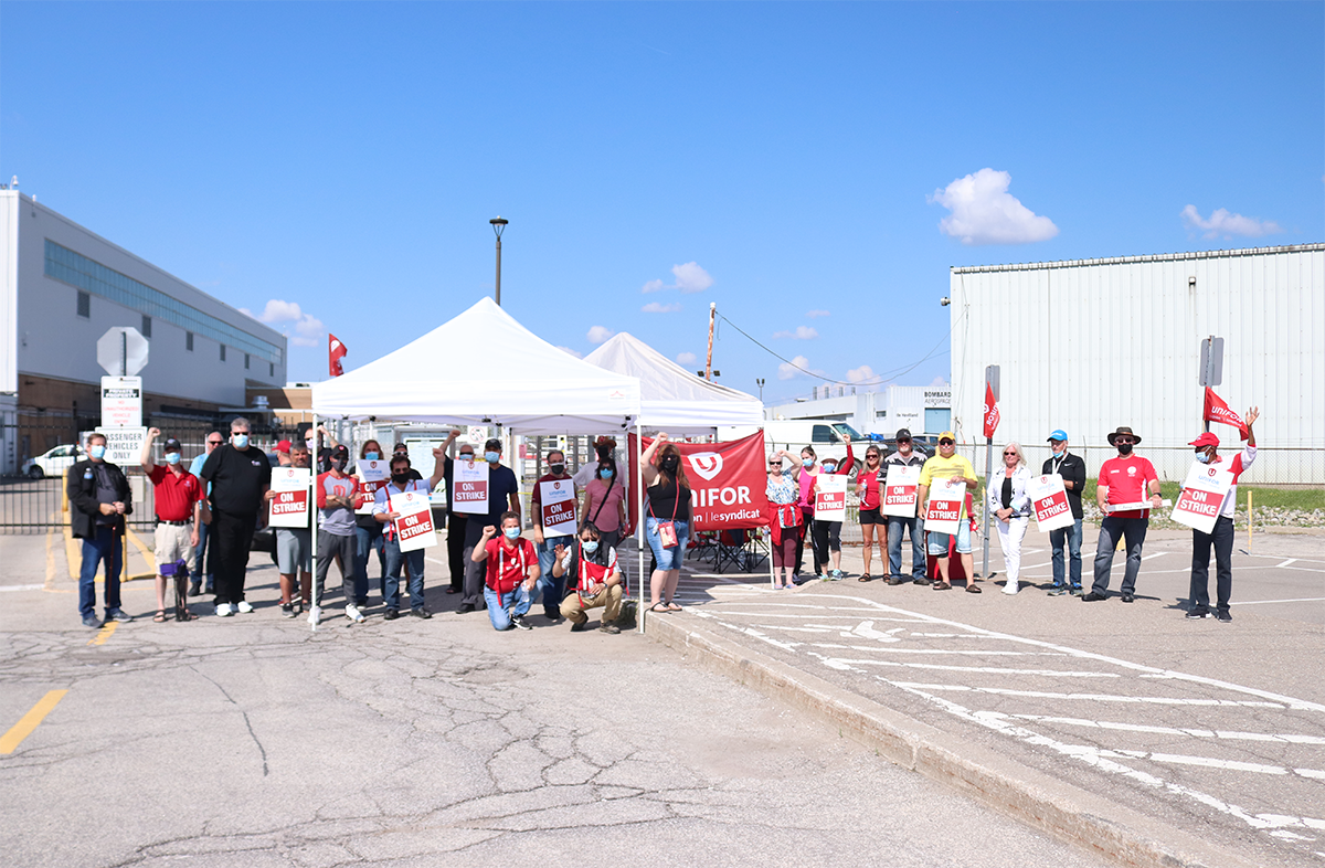 Unifor members holding strike signs and flags on a picket line at Downsview.