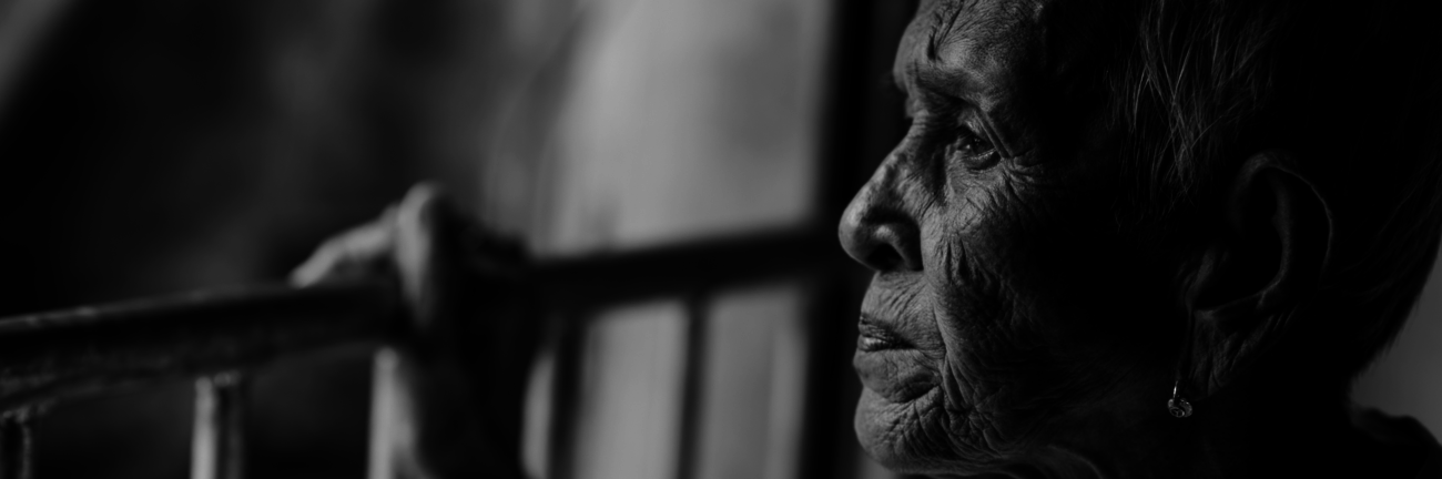 A older women looking out off a balcony with her hand on the railing.