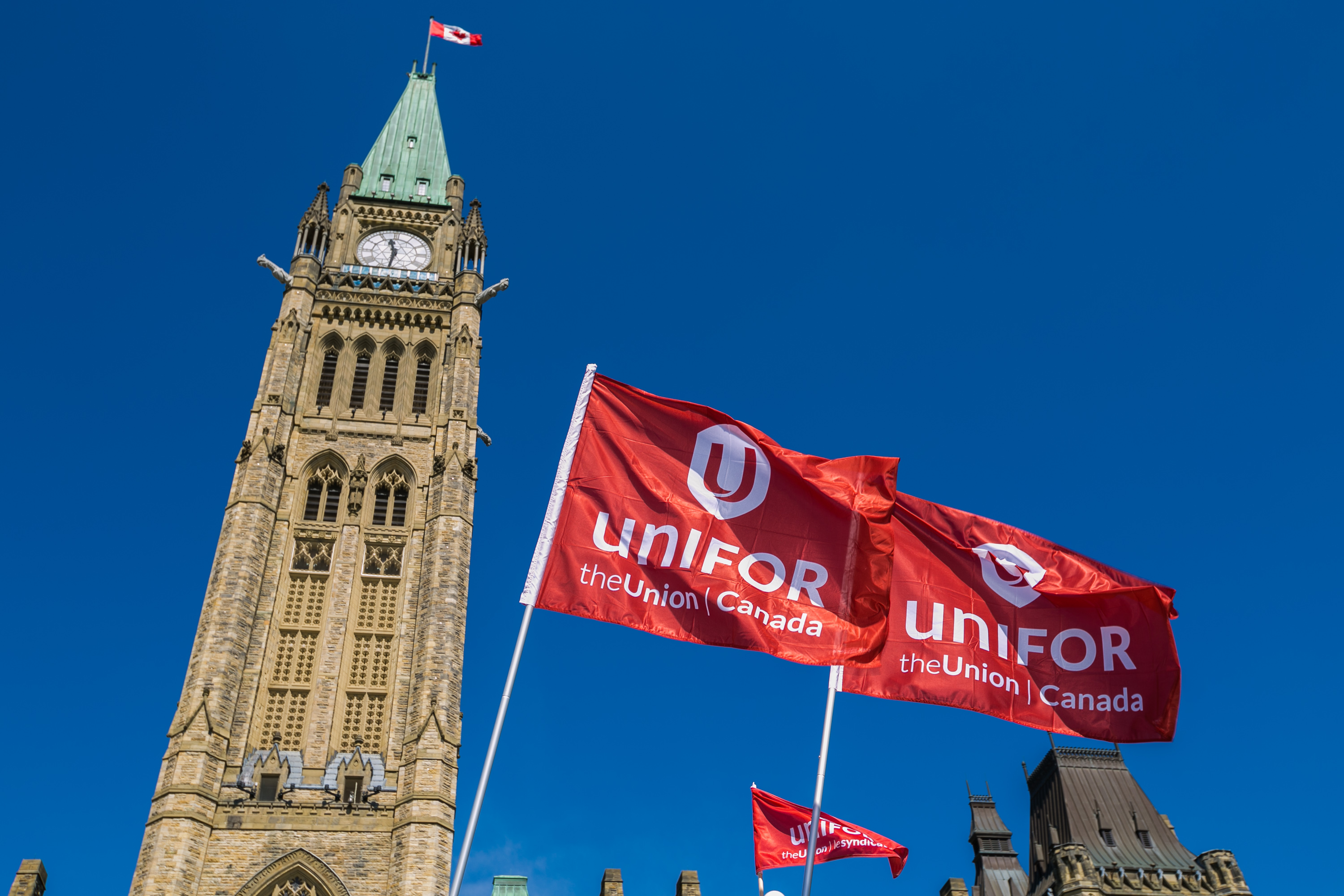 Two Unifor flags fly in front of the Peace Tower in Ottawa, Ontario.