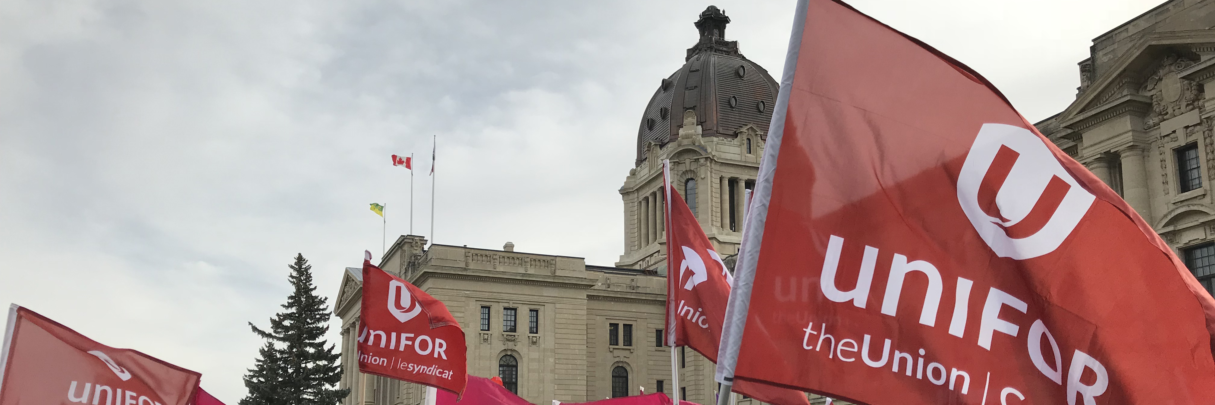 Unifor flags wave in front of the Saskatchewan legislature building.