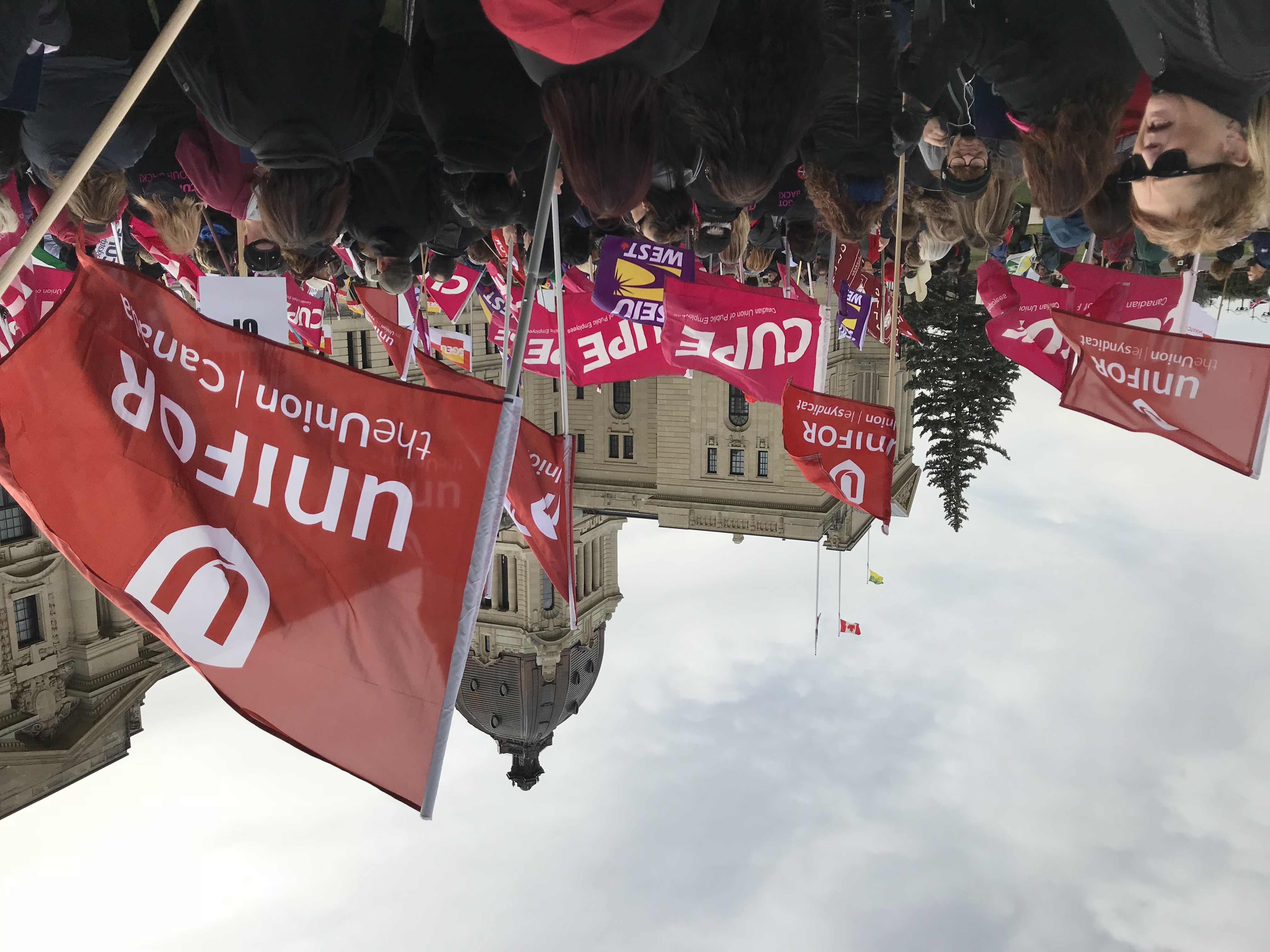 A crowd of Union activists wave flags in front of the Saskatchewan legislature.