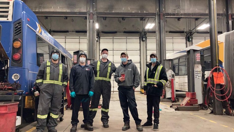 five men standing wearing work coveralls