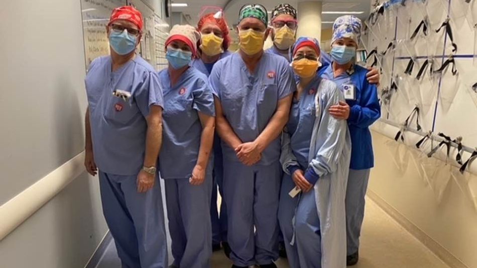 Health care workers stand six feet apart in hospital cafeteria.