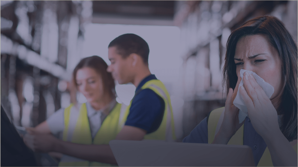 A worker blows their nose with two co-workers seen in the background.