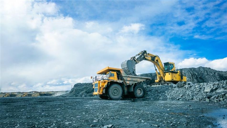 excavateur industriel chargeant un camion-benne en plein air dans un paysage rocheux gris