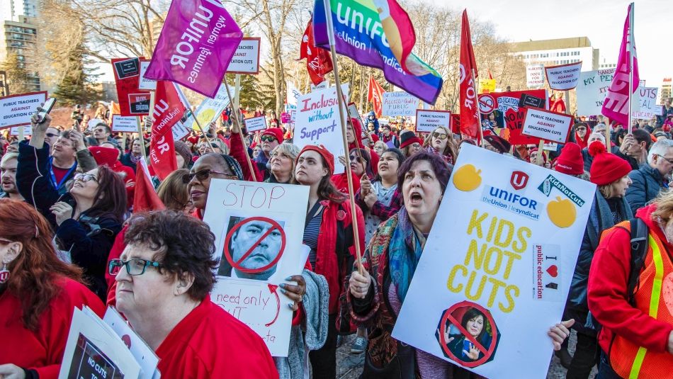 Grande foule lors d’un rassemblement avec des membres d’Unifor tenant des pancartes et des drapeaux au premier plan