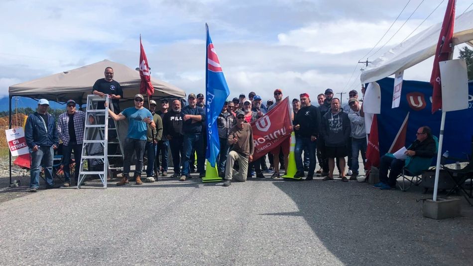 Large group on picket line with signs and flags