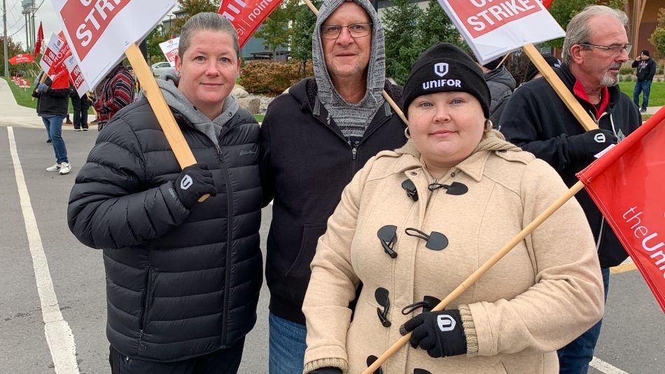 Group of three striking workers outside with flags and placards