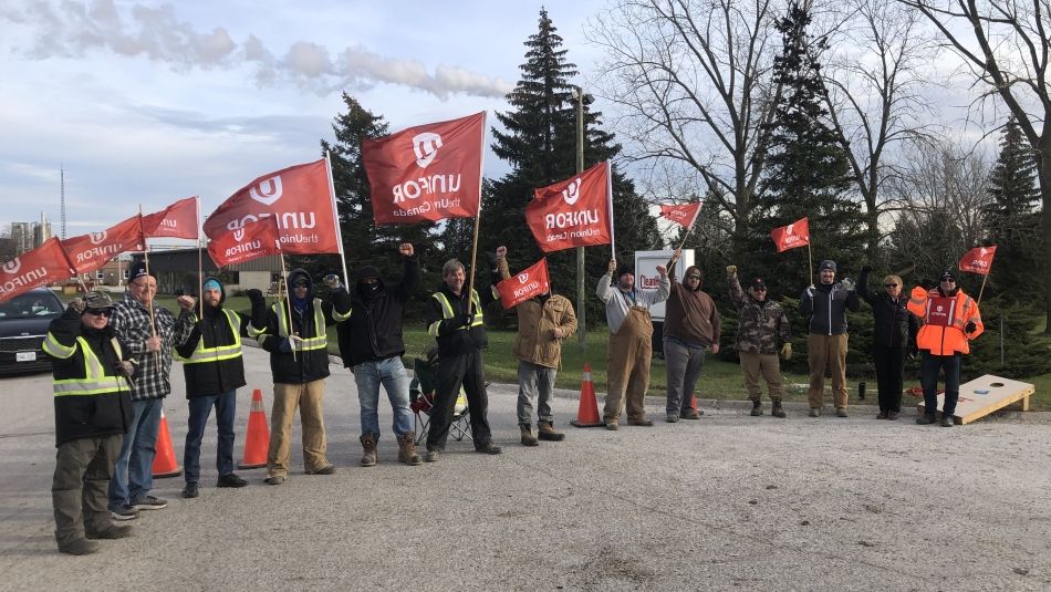 Line of workers on a picket line holding flags blowing in the wind
