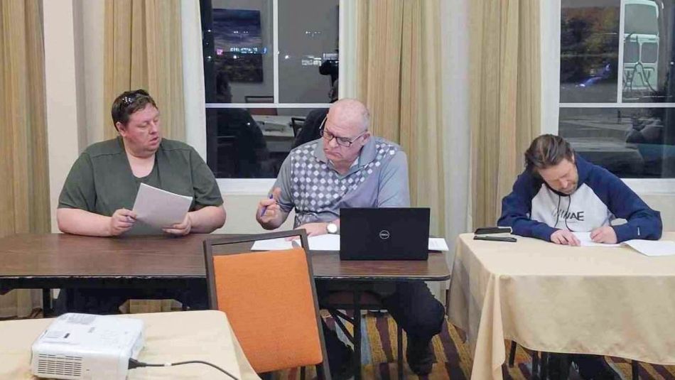 Local 1839 bargaining committee Three people sitting and working at a meeting room table.