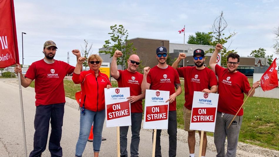 Membres d’Unifor brandissant des pancartes de grève, poings en l’air