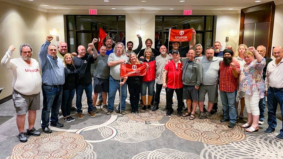 A large bargaining committee standing and posing for a photo with fists in the air