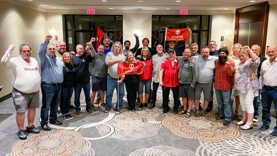 Two dozen members of the Loomis bargaining committee posing inside, some with flags and fists in the air