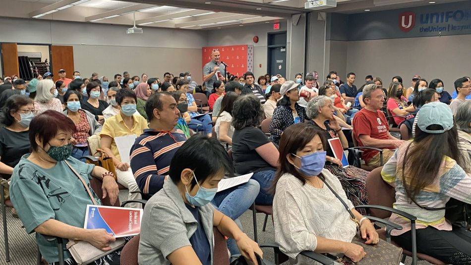 Room full of Unifor members seated classroom style. On member is standing speaking into microphone at far side of the room.