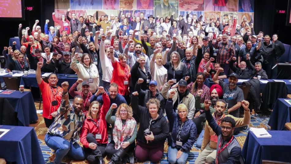 Large crowd of delegates posing for a photo with their fists in the air