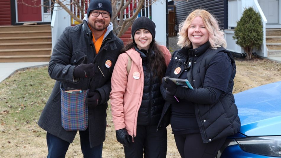 "Trois personnes à l'extérieur sourient et posent pour une photo."