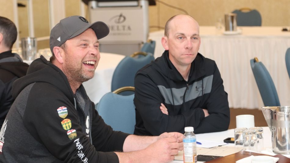 Two men sitting at a table smiling at a BWP meeting