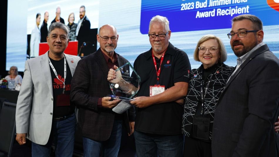 Five people standing together one holding an award.