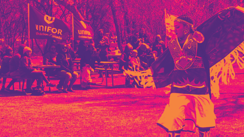 Indigenous dancer in regalia with an outdoor audience seated in the background