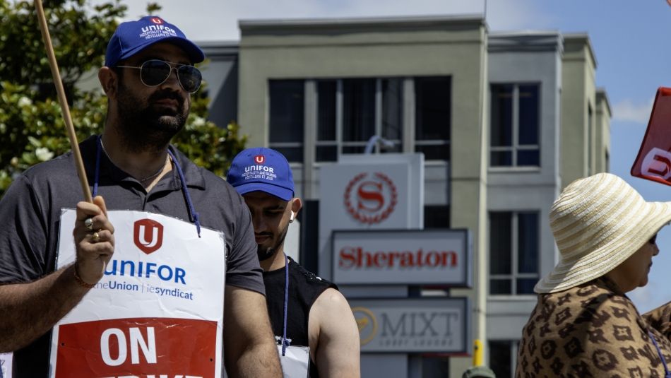 Striking members on a picket line wearing "On Strike" signs