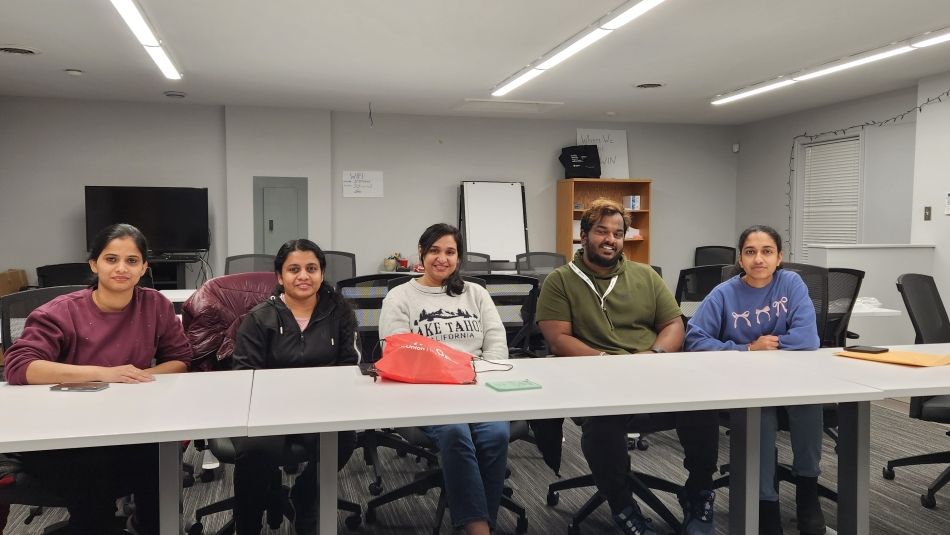 Five people sitting behind tables in a boardroom