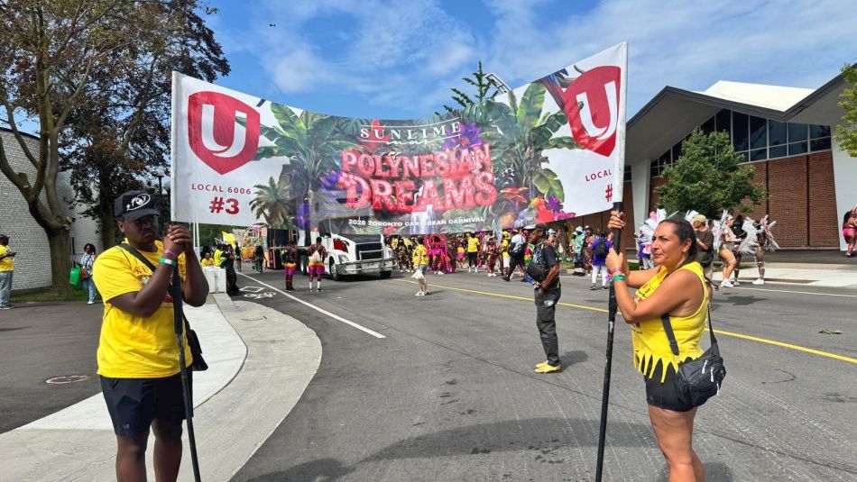 Two people holding up a banner with festival attendees in the background