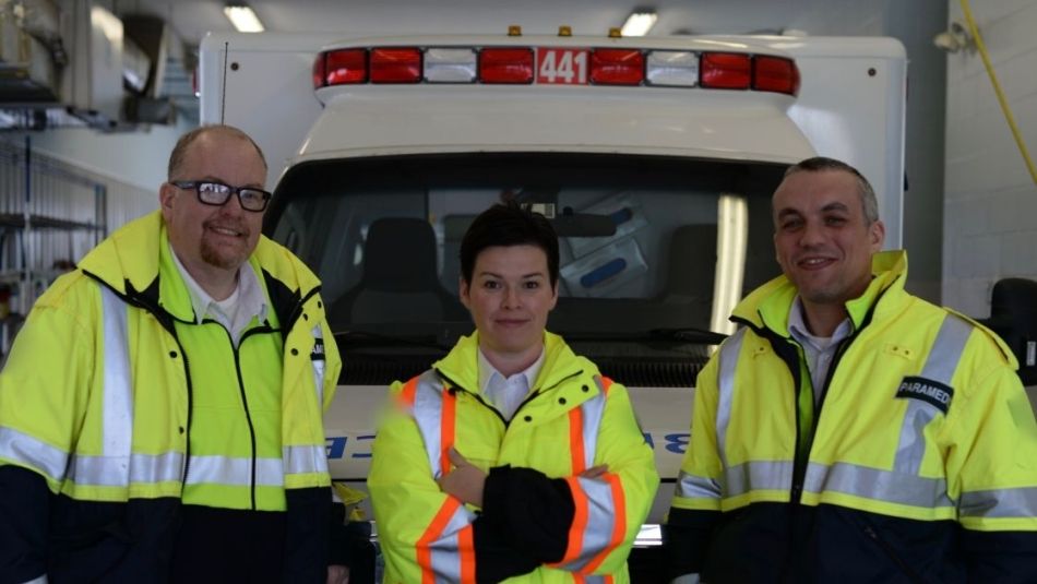 Three paramedics in front of an ambulance