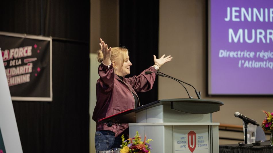 A women arms raised speaking at a podium